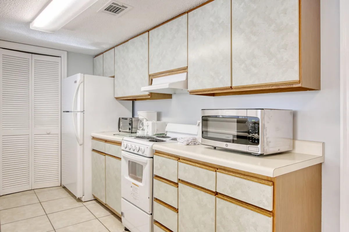 A practical, fully equipped kitchen with a stove, refrigerator, microwave, and ample cabinetry. The space feels homely and ready for family cooking sessions, with a layout ideal for group meal preparation or baking together.